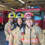 Fire fighters standing in front of firetrucks